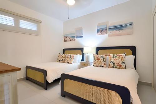 two beds in a room with white walls at Caribbean Sunscape Beachfront Apartment in La Puntica de Juan Dolio