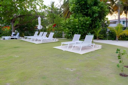 a group of white lounge chairs on a lawn at Caribbean Sunscape Beachfront Apartment in La Puntica de Juan Dolio
