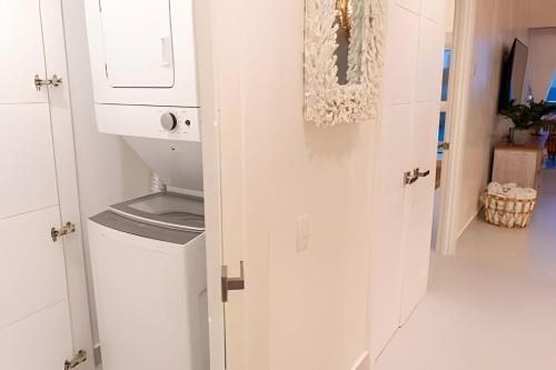 a white laundry room with a washer and dryer at Caribbean Sunscape Beachfront Apartment in La Puntica de Juan Dolio