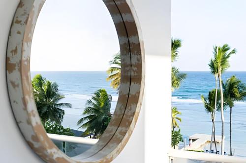 a circular window with a view of the ocean at Caribbean Sunscape Beachfront Apartment in La Puntica de Juan Dolio