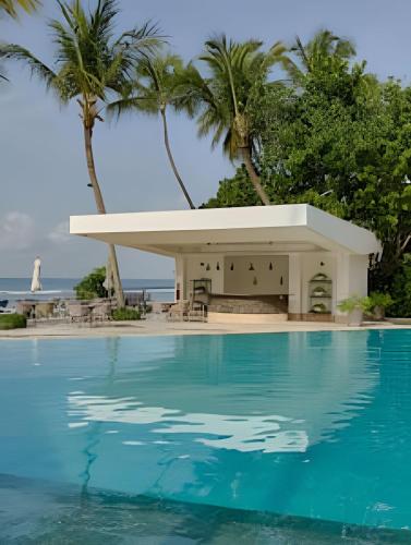 a resort with a swimming pool and palm trees at Caribbean Sunscape Beachfront Apartment in La Puntica de Juan Dolio