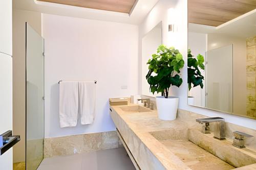 a bathroom with two sinks and a potted plant at Caribbean Sunscape Beachfront Apartment in La Puntica de Juan Dolio