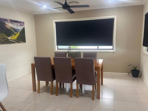 a dining room with a table with chairs and a flat screen tv at Holiday Home in Branxton