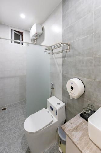 a white bathroom with a toilet and a sink at The Morris Central Hotel - O'TEL in Da Lat