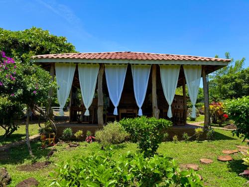 a pavilion in a garden with white curtains at Finca Montaña Sagrada in Mérida