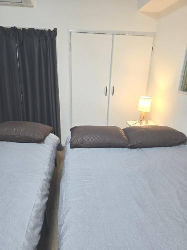 a bedroom with two beds and a lamp on a table at 道頓堀徒歩5分ss3 in Osaka