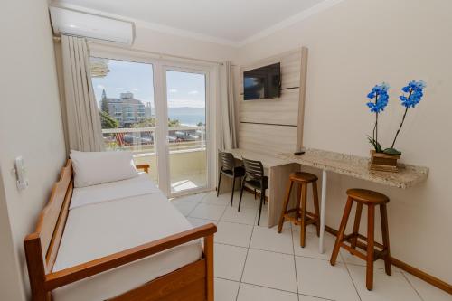 a room with a bed and a kitchen with a window at Hotel Monteiro Canasvieiras in Florianópolis