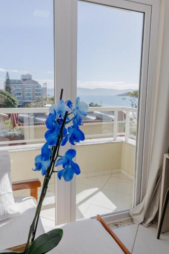 a blue flower sitting on a table in front of a mirror at Hotel Monteiro Canasvieiras in Florianópolis