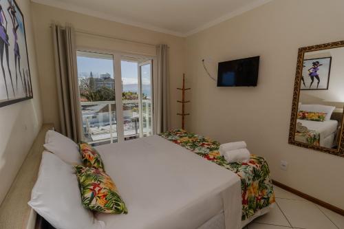 a bedroom with a bed and a view of the ocean at Hotel Monteiro Canasvieiras in Florianópolis