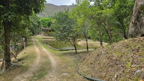 a dirt road next to a pond with a hose at Finca El Encanto in Melgar