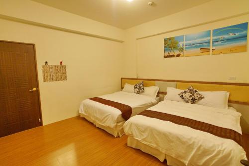 a hotel room with two beds and a door at Bang Qiaonuo - Peng's family in Taitung City