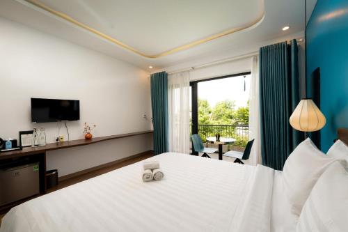 a hotel room with a large bed and a window at Hoianese Sunset Serenity Hotel in Hoi An