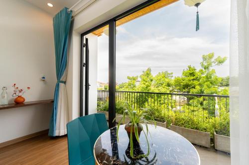 a dining room with a glass table and a large window at Hoianese Sunset Serenity Hotel in Hoi An