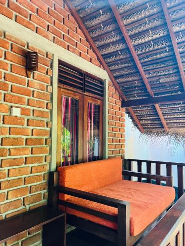 an orange bench sitting on the side of a brick wall at Ganesh Garden Beach Cabanas in Tangalle