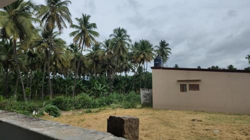 a white building with palm trees in the background at Pine Stay in Alāndurai