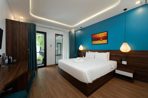 a bedroom with a white bed and a blue wall at Hoianese Sunset Serenity Hotel in Hoi An
