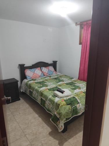 a bedroom with a bed with a green comforter at Hotel La Terraza Raquireña in Ráquira