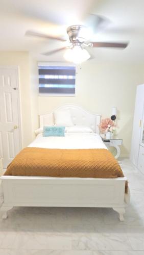 a white bedroom with a bed and a ceiling fan at Staten Island Cozy Private 1-br Basement Apt close to NYC Family & Pet Friendly in Willowbrook