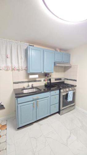 a kitchen with blue cabinets and a stove at Staten Island Cozy Private 1-br Basement Apt close to NYC Family & Pet Friendly in Willowbrook