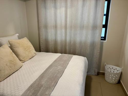 a bedroom with a white bed with a window at The Gateway Getaway in Durban