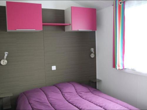 a purple bed in a room with a window at Mobil-home avec terrasse à Bretignolles-sur-Mer, 6 pers., 3 chambres - API-1-52-389 in Brétignolles-sur-Mer