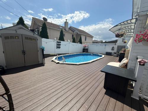 a backyard with a swimming pool on a wooden deck at Staten Island Cozy Private 1-br Basement Apt close to NYC Family & Pet Friendly in Willowbrook