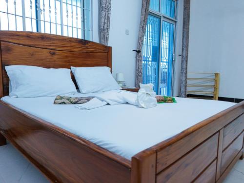 a large bed with white sheets and a wooden headboard at Spacious Beachfront Condo -AC - WiFi, Uroa Escape Zanzibar in Uroa