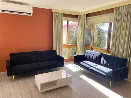 a living room with a black couch and a table at Lakeside 2-Bedroom Villa in Lakes Entrance