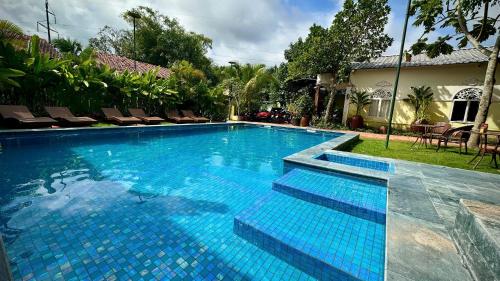 a large blue swimming pool with chairs and a house at Song Ngư Riverside Homestay in Can Tho