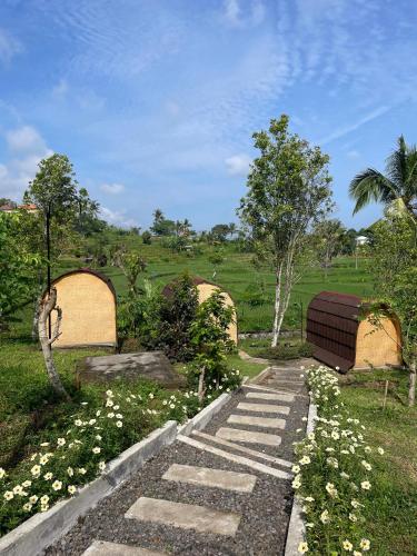 a stone path in a garden with flowers and trees at Tranquil Riverside Camping in Ambengan