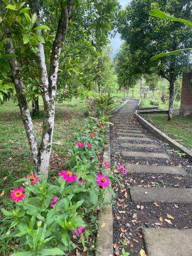 a garden with pink flowers on a stone path at Tranquil Riverside Camping in Ambengan
