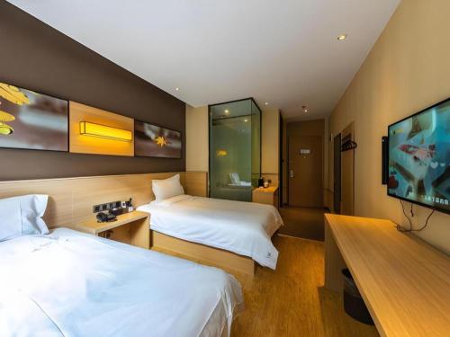 a hotel room with two beds and a flat screen tv at IU Hotel Kunming Jinma Bijifang Joy City in Kunming