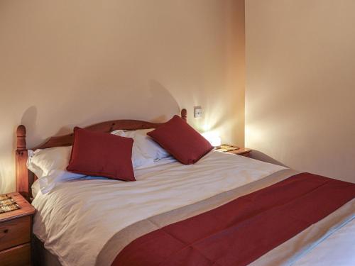 a bedroom with a bed with two red pillows on it at Plas Madog in Llanuwchllyn