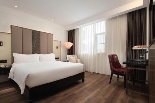 a hotel room with a large bed and a desk at Jinjiang Metropolo Haikou East High Speed Railway Station Normal University in Haikou