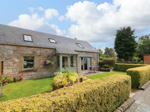 an old stone house with a garden and bushes at Muirmailing Cottage in Plean