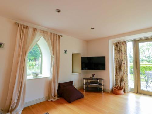 a living room with a tv and a window at Muirmailing Cottage in Plean