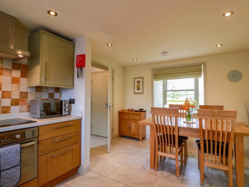 a kitchen with a table and chairs and a microwave at Muirmailing Cottage in Plean