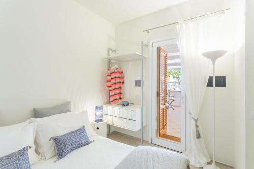 a white bedroom with a white bed and a window at Suite Faro 33 in San Vito lo Capo