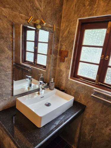 a bathroom with a white sink and a mirror at The Villa at Galapitiyaya Estate in Haputale