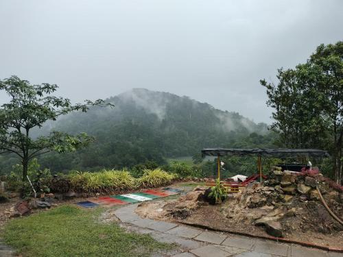 a garden with a table and a mountain in the background at Homestay LubokSawah in Pekan Nanas
