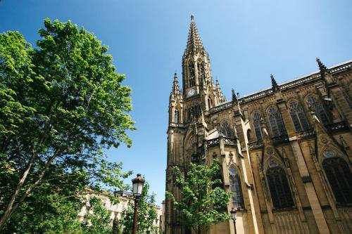 a large cathedral with a tower and a tree at Hostal San Ignacio Centro in Donostia-San Sebastián