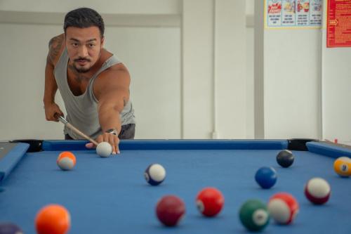 a man playing a game of pool with a cue at The Up Hotel Phu Quoc Island - The Poolside Escape in Phu Quoc