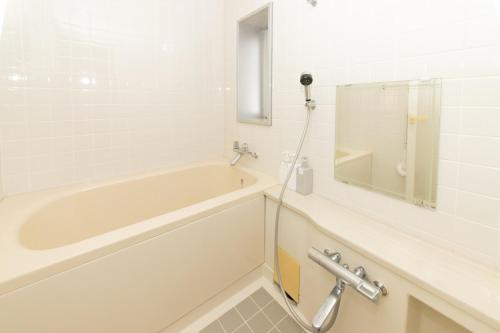 a white bathroom with a tub and a shower at ゲストハウスsimasima西宝町301 in Takamatsu