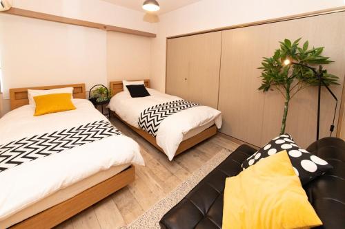 two beds in a room with a couch at ゲストハウスsimasima西宝町301 in Takamatsu