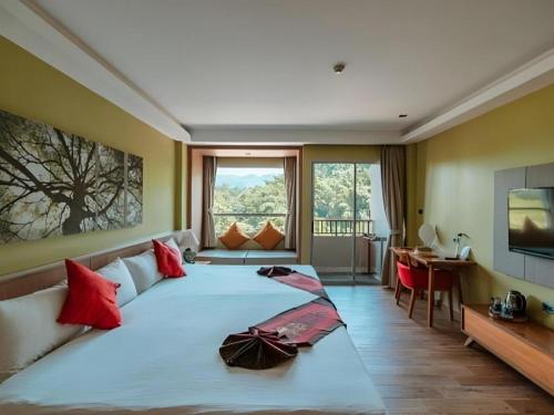 a large bedroom with a large white bed with red pillows at River Kwai Village Hotel in Ban Kaeng Raboet