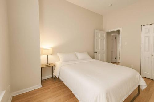 a white bed in a room with a lamp on a table at Soulard 2BR Balcony Free Parking Walk to Dining in Soulard