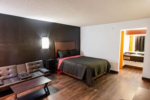 a bedroom with a bed and a couch at Rose City Inn & Suites in Oak Grove