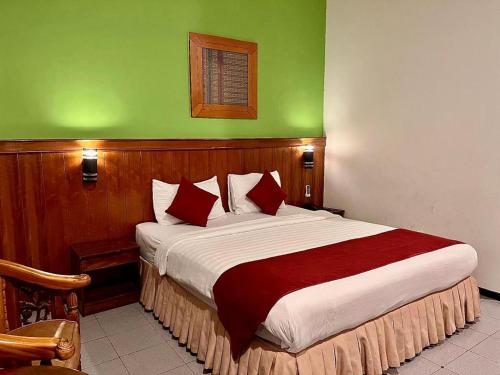 a bedroom with a large bed with a green wall at Garuda Hotel Pontianak in Pontianak