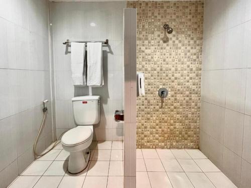 a bathroom with a toilet and a shower with towels at Garuda Hotel Pontianak in Pontianak