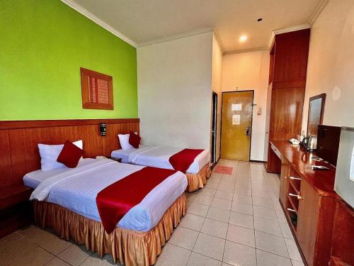 two beds in a hotel room with green walls at Garuda Hotel Pontianak in Pontianak